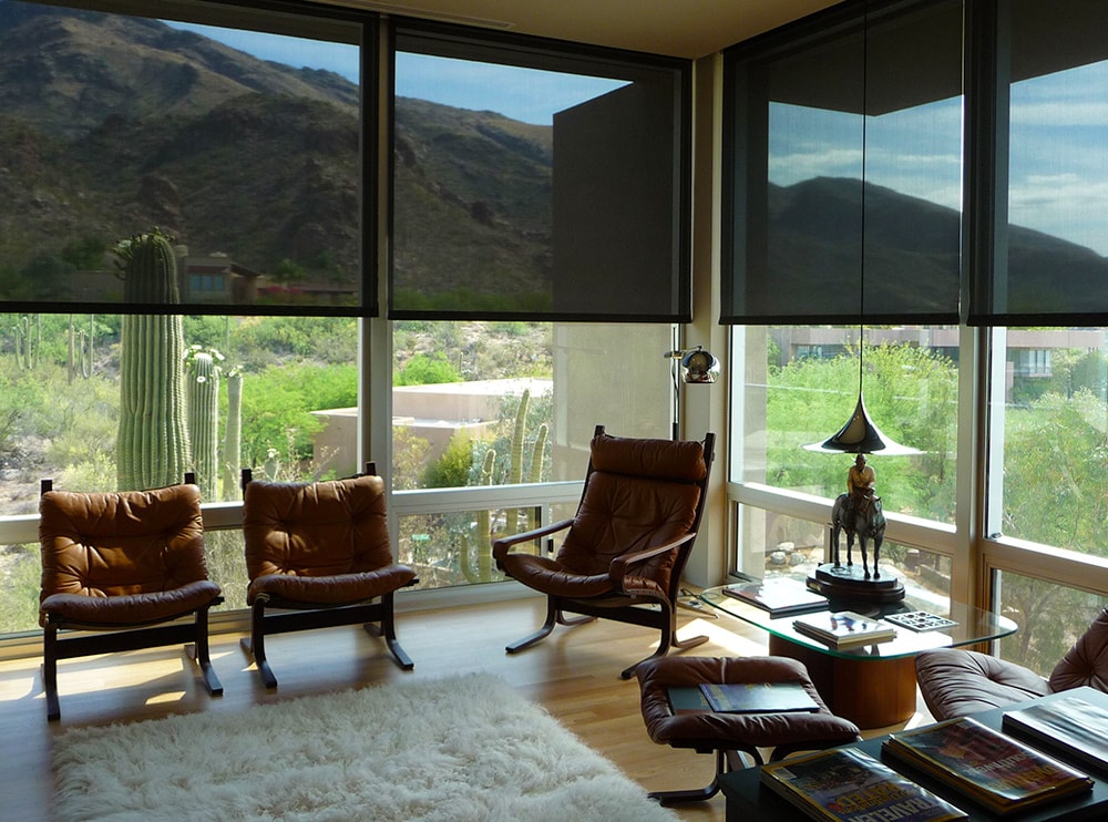 View from inside a screened room with Freedom screens lowered over full-height glazing, looking out to a desert landscape