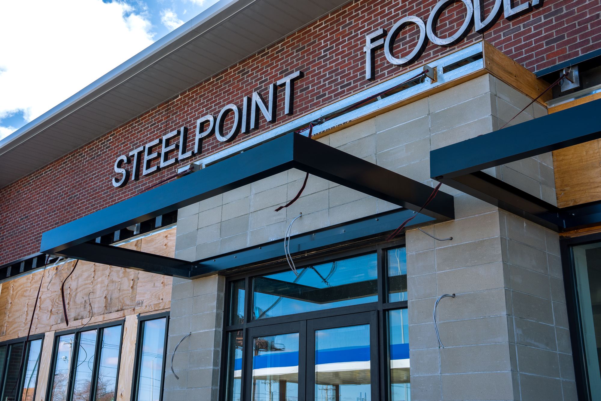 Fixed blade canopies in dark navy over a retail entrance and windows on a brick and stone frontage