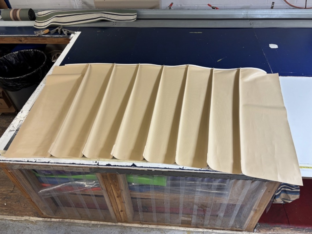 A Metal Look panel laid flat on a fabrication table before the skin is tensioned, showing the formed standing-seam ribs